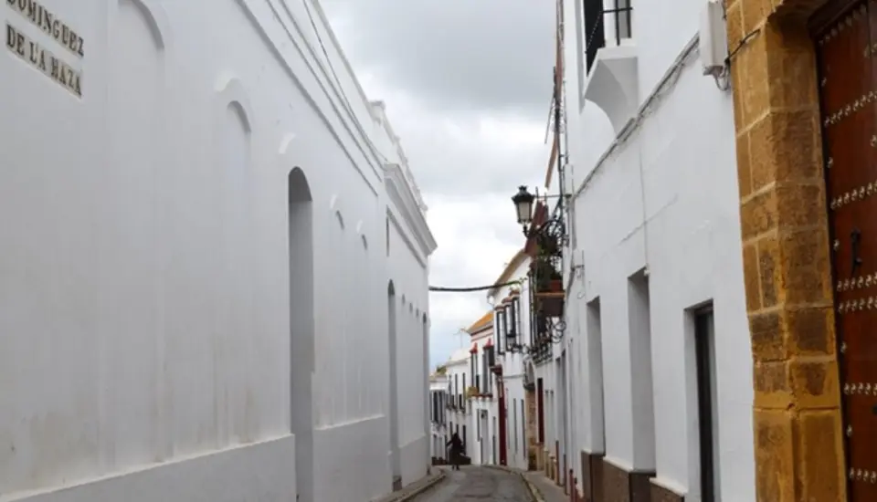 Calle de origen islámico (Carmona) 1 Calle estrecha con paredes blancas y cielo nublado.