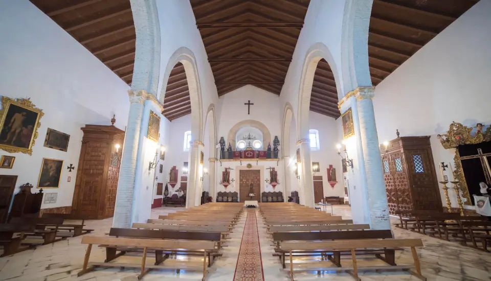 Iglesia gótico-mudéjar de San Bartolomé (Carmona) Interior de iglesia con arcos y bancos de madera.