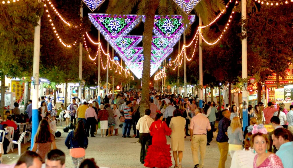 Gente paseando en feria nocturna iluminada.