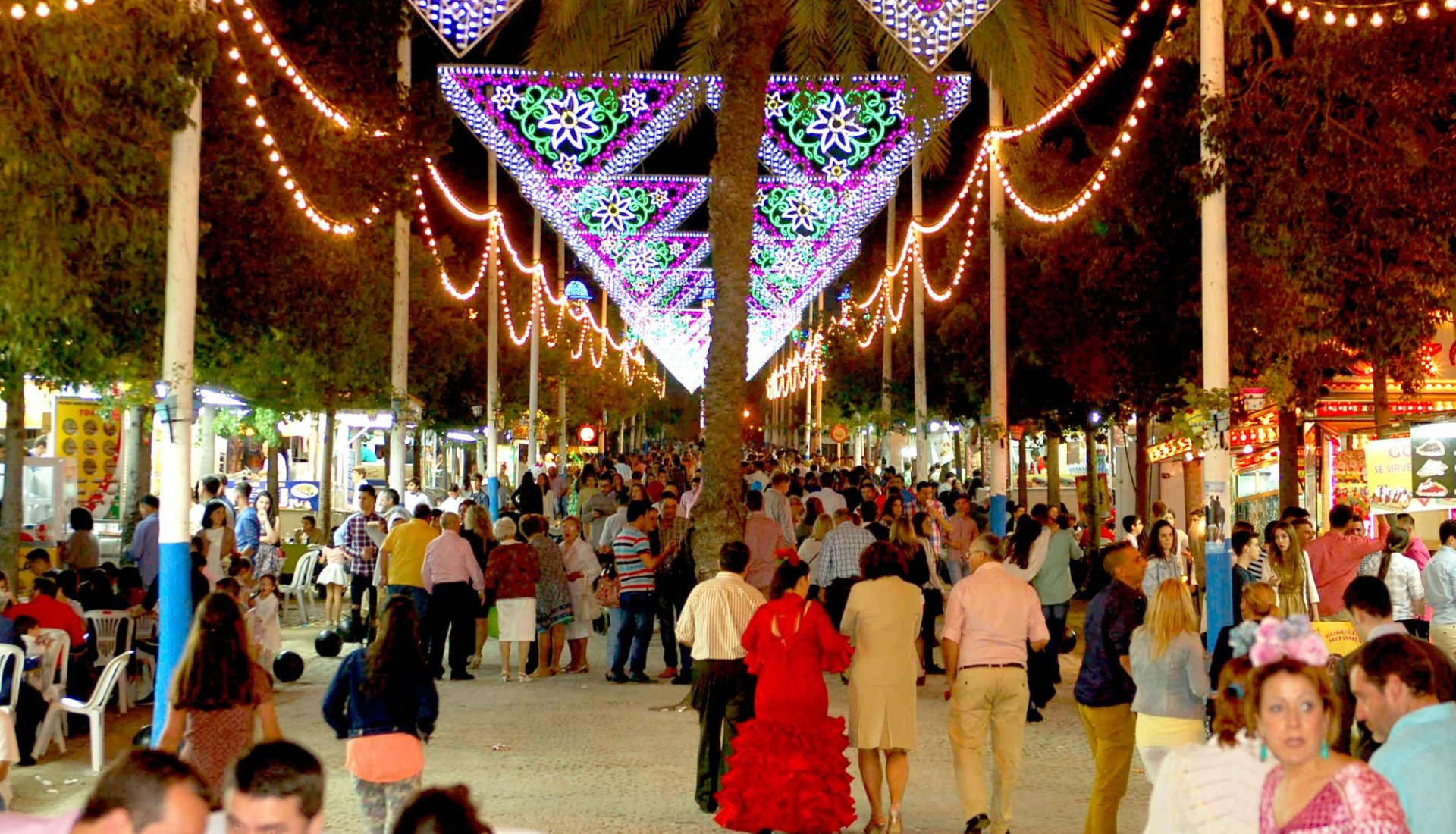 Gente paseando en feria nocturna iluminada.