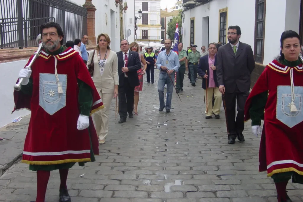 Procesión en calle con personas en traje formal.